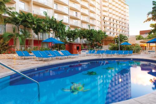 a swimming pool at a hotel with chairs and umbrellas at Wyndham Waikiki Beach Walk 2BR Apartment with Resort Access in Honolulu