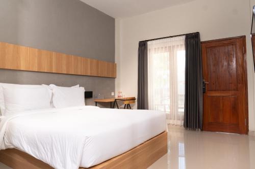 a bedroom with a large white bed and a window at Maluk Stay in Maluk