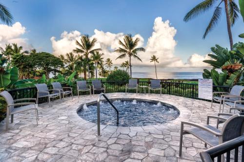 a hot tub with chairs and the ocean in the background at Wyndham Kona Coast Resort 2BR Apartment with Resort Access in Kailua-Kona