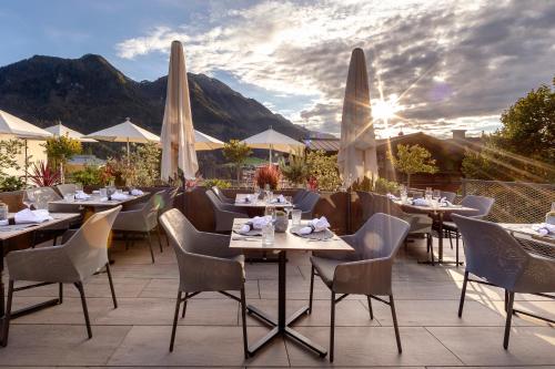 a restaurant with tables and chairs on a patio at Aktivhotel Alpendorf in Sankt Johann im Pongau