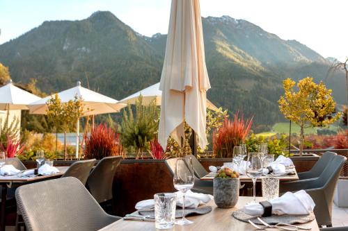 a restaurant with tables and chairs with mountains in the background at Aktivhotel Alpendorf in Sankt Johann im Pongau