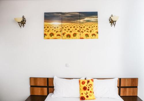 a room with a bed with a painting of a field of sunflowers at Pensiunea de la Rau Moieciu de sus in Moieciu de Sus
