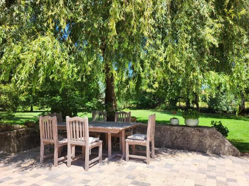 a wooden table with four chairs and a tree at Le Bastion in Marnay