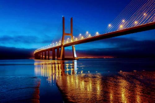 a bridge over a body of water at night at Comfort Relax & Explore Vasco da Gama, Expo Lisbon in Lisbon