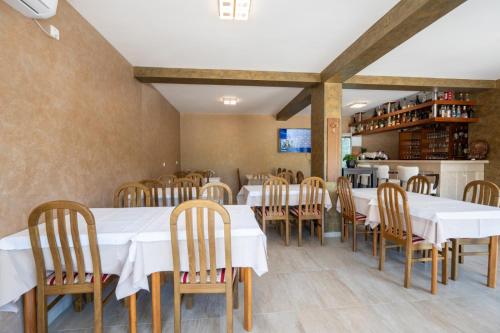 a dining room with white tables and wooden chairs at Apartmani Bonaca Neum in Neum