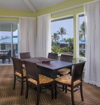 a dining room with a table and chairs and windows at Holua Resort at Mauna Loa 1BR Apartment with Resort Access in Kailua-Kona