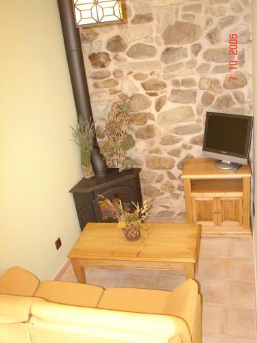 een woonkamer met een bank en een stenen muur bij El Refugio de la Sauca in Alameda del Valle