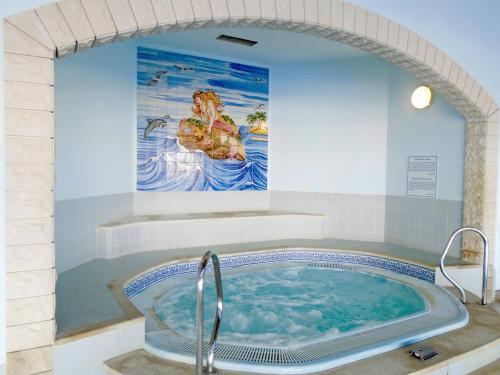 a tub in a bathroom with a painting on the wall at Family Escape, oasis parque in Portimão