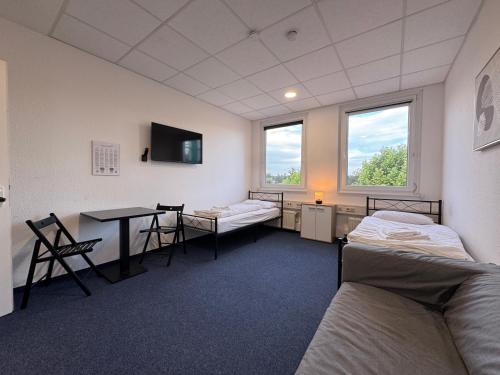 a room with two beds and a table and chairs at Thuja Apartments Karlsruhe-Neureut by KurzZeit in Karlsruhe