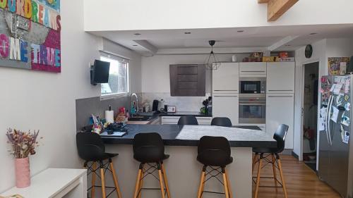 a kitchen with a island with bar stools at Maison loft Côte de Granit Rose in Saint-Quay-Perros