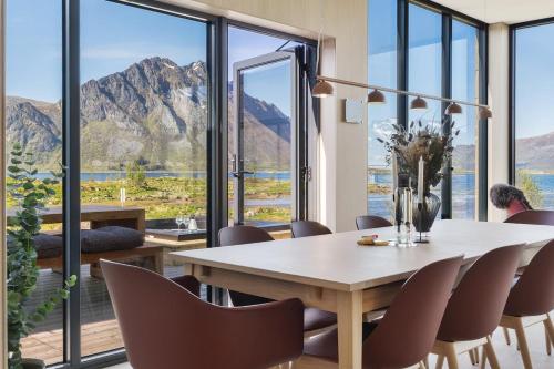 a dining room with a table and chairs and mountains at NEW - Seafront Luxury Villa near Henningsvær in Kleppstad