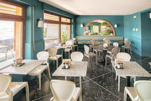 a restaurant with tables and chairs and a mirror at Albium Hotel in Albenga