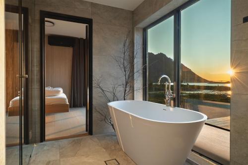 a bath tub in a bathroom with a view of a bedroom at NEW - Seafront Luxury Villa near Henningsvær in Kleppstad