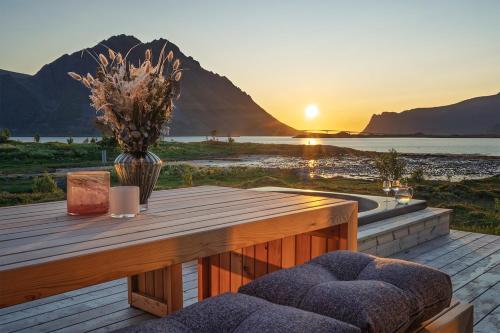 a wooden deck with a table with a vase of flowers at NEW - Seafront Luxury Villa near Henningsvær in Kleppstad