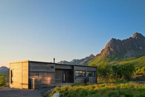 a wooden house with mountains in the background at NEW - Seafront Luxury Villa near Henningsvær in Kleppstad