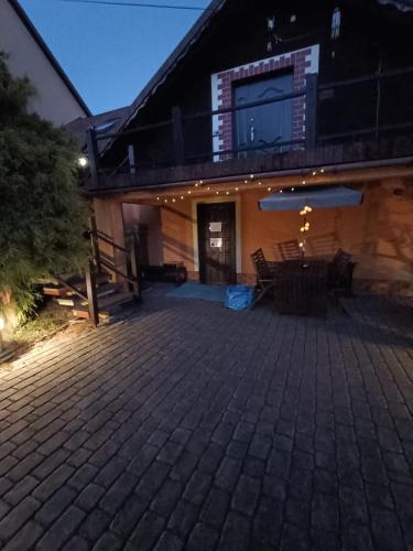 a house with a brick patio at night at Agroturystyka Rudy Kocur Różana 24 Jaroszowice in Jaroszowice