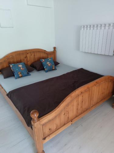 a wooden bed with blue pillows on top of it at Agroturystyka Rudy Kocur Różana 24 Jaroszowice in Jaroszowice
