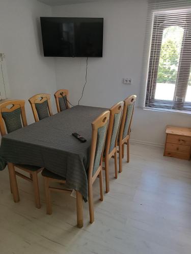 a dining room table with chairs and a television on a wall at Agroturystyka Rudy Kocur Różana 24 Jaroszowice in Jaroszowice