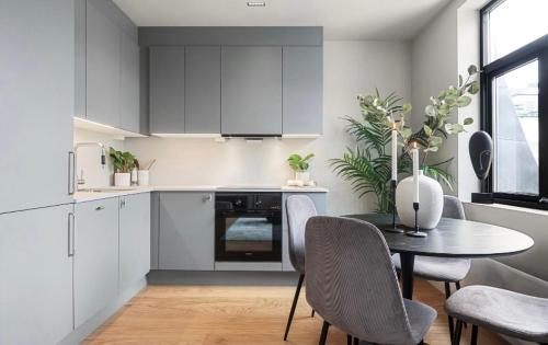 a kitchen with white cabinets and a table with chairs at New apartment at Majorstuen in Lii