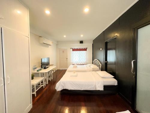 a hotel room with two beds and a desk at White Lodge Hotel Bangkok in Bangkok