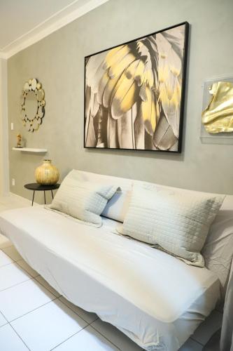 a bedroom with a white bed with a painting on the wall at Apartamento Atalaia Aracaju 3 quartos in Aracaju