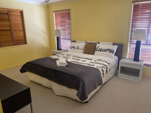 a bedroom with a large bed and two windows at Amazing Perfect Family Home - GC Beach location in Gold Coast