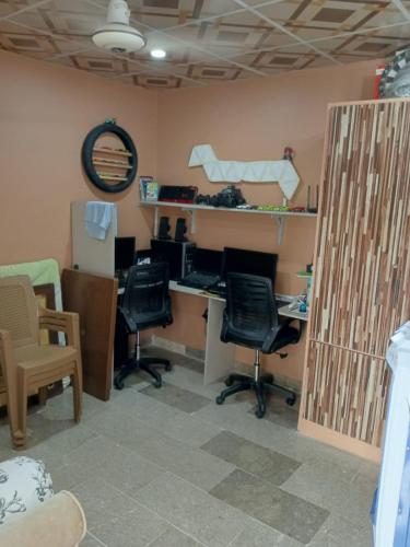 ein Büro mit Stühlen und einem Schreibtisch mit einem Computer in der Unterkunft FASTCOM Flat in Karatschi