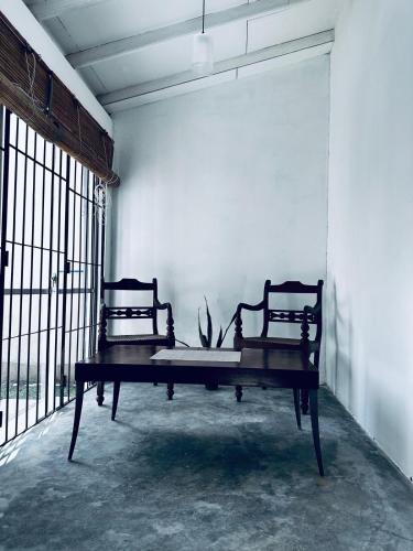 a table in a room with two chairs and a wall at Frangipani House in Oruwala