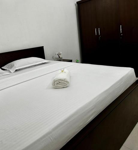 a white bed with a white towel on it at Frangipani House in Oruwala