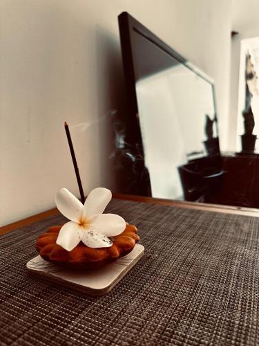 a white flower on a plate on a table at Frangipani House in Oruwala