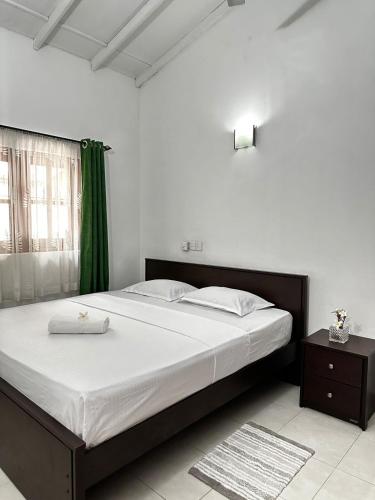 a bedroom with a large bed and a green curtain at Frangipani House in Oruwala