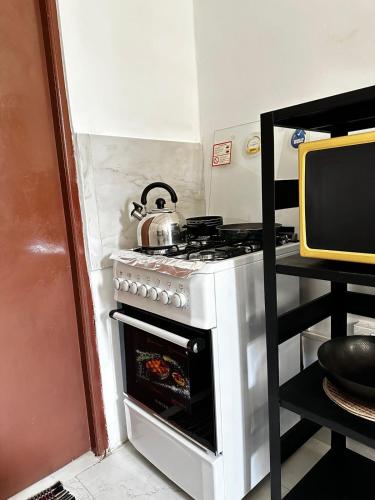 a kitchen with a stove with a tea kettle on it at Frangipani House in Oruwala
