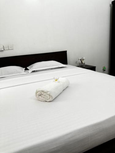 a white towel laying on a white bed at Frangipani House in Oruwala