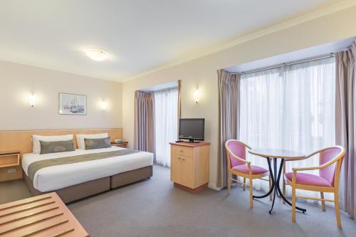 a hotel room with a bed and a table and chairs at The Waverley International Hotel in Glen Waverley