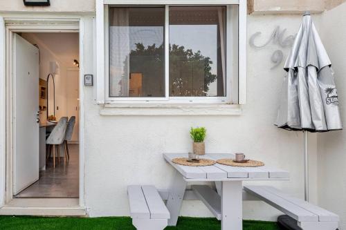 a white table and bench next to a window at GW009 Gugel Waves Patio and Pool Seaview Apartment in Nahariyya