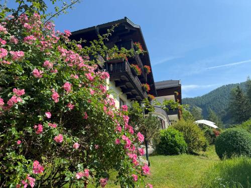 a building with pink flowers in front of it at Pension & Appartements Ronacherhof -Mountain Hideaway Slopeside in Bad Kleinkirchheim