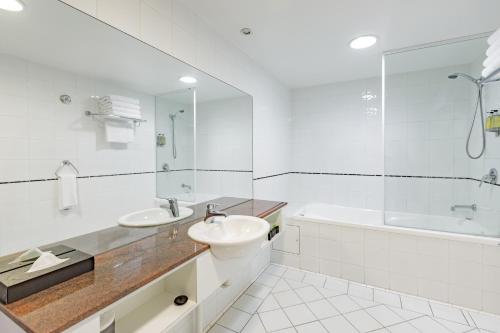 a white bathroom with a sink and a tub at The Waverley International Hotel in Glen Waverley