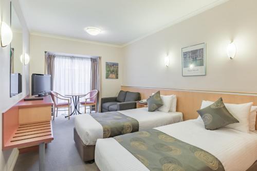 a hotel room with two beds and a table at The Waverley International Hotel in Glen Waverley