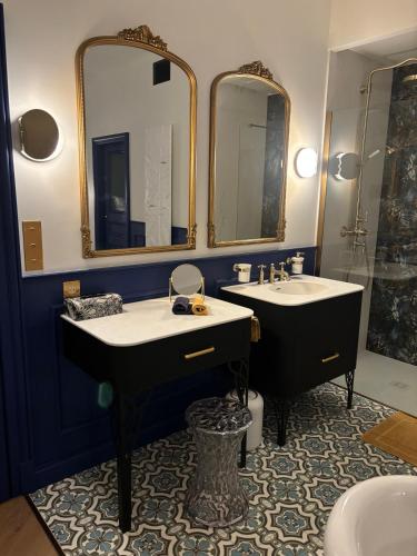 a bathroom with two sinks and two mirrors at Les Ecuries de Rigny, Suite haut de gamme avec jardin, jacuzzi et piscine in Nancy