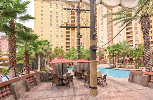 a resort with a pool and tables and chairs and palm trees at Wyndham Bonnet Creek 2BR Apartment with Resort Access in Orlando