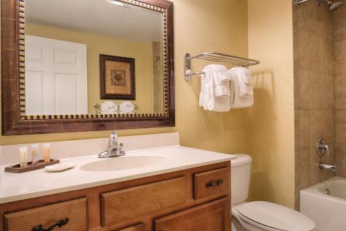 a bathroom with a sink and a toilet and a mirror at Wyndham Bonnet Creek 2BR Apartment with Resort Access in Orlando