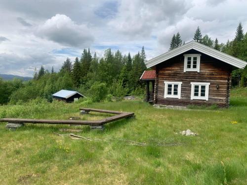 a small wooden cabin in a field with a bridge at Beautiful place among forests and fields in a good old style in Eggedal