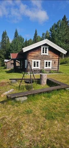 a log house with a playground in front of it at Beautiful place among forests and fields in a good old style in Eggedal