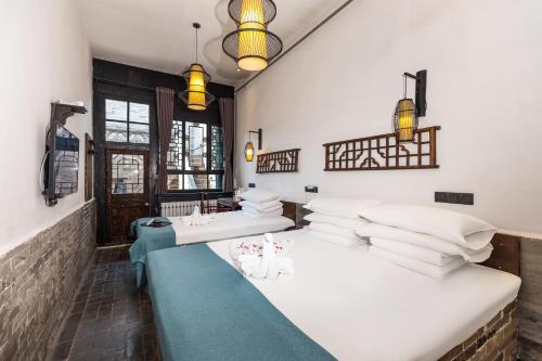 a room with three beds with white pillows at Elsewhere Hotel The former residence of the draft bank in Pingyao