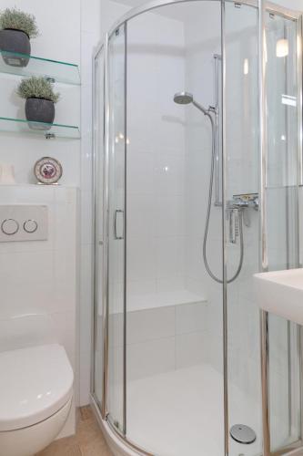 a white bathroom with a shower and a toilet at Ferienwohnung mitten in Westerland mit Balkon in Westerland