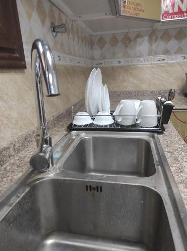 a kitchen sink with plates and pans on a rack at Elegant Ap in Muscat