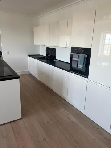 a kitchen with white cabinets and black counter tops at Lækker lejlighed på havnefronten 1 in Nakskov