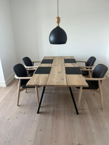 a dining room table with chairs and a black pendant at Lækker lejlighed på havnefronten 1 in Nakskov