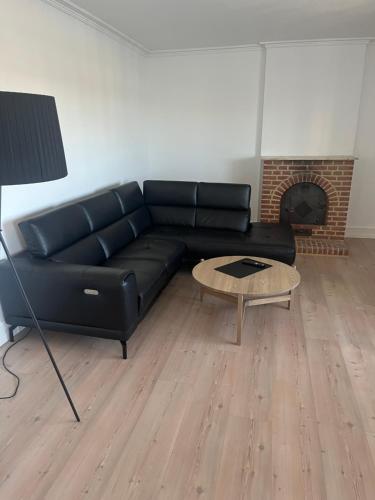 a black leather couch in a living room with a fireplace at Lækker lejlighed på havnefronten 1 in Nakskov