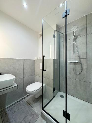 a bathroom with a glass shower and a toilet at Ferienwohnung zwischen den Dünen in Rantum